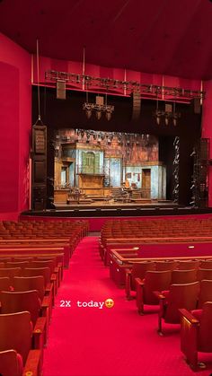 an empty auditorium with red carpet and chairs