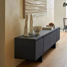 a living room with a large painting and two vases on top of a dresser