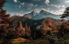 the mountains are covered with trees and grass, as well as clouds in the sky