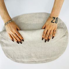 a woman's hands with black nail polish and tattoos on her arms sitting in a chair cushion