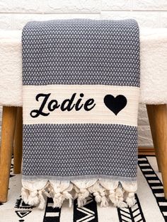 a black and white towel with the word jodie on it sitting on top of a wooden chair