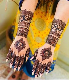 a woman's hands with henna tattoos on her arm and hand, showing the intricate design