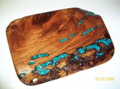 a wooden cutting board with blue beads on it's edges and some wood in the middle