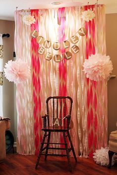 a chair sitting in front of a curtain with pink and gold decorations on it's side