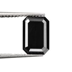 a black diamond is being held by a pair of tongs on a white background