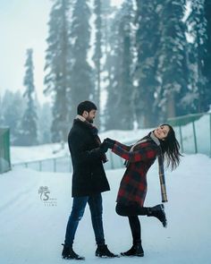 two people standing in the snow with one holding the other's hand and smiling