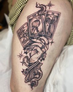 a woman's thigh with tattoos on it and three playing cards in the middle