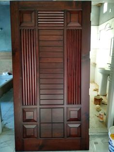 an open wooden door in the middle of a room with tile flooring and walls