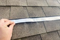 a person holding a piece of tape on top of a roof