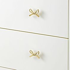 a white dresser with two gold handles on it