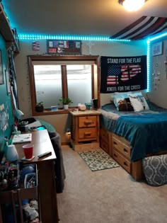 a bedroom with a bed, desk, and window in the corner is lit up by blue lights