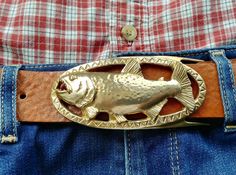 "Handcrafted in Brass, this Golden Dorado Buckle sports a Chestnut handmade bridle leather belt.  The Golden Dorado, South America's largest and most fierce, fresh water fish is captured here in yellow brass to mimic the golden color of the flashing fish on the fly.  Inhabiting the rivers and marshes of Brazil, Paraguay, Uruguay, Bolivia and northern Argentina, the River Tiger is sought after by \"Catch and Release\" anglers for its beauty and fierce fight.   The elliptical shaped buckle showing Dorado Fish, Tiger Fish, Catch And Release, Nice Belts, Organic Nature, Chestnut Color, Brown Belt, Suspender Belt, Golden Color