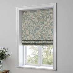 a window with a blue and white patterned roman blind in front of the window, next to a potted plant