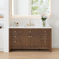 a bathroom with a large mirror above the sink and wooden cabinet below it, in front of a window