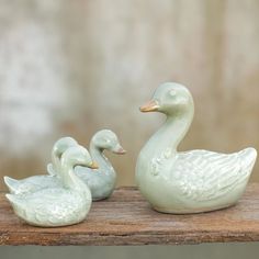 two ceramic ducks sitting on top of a wooden table