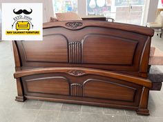 a wooden bed frame with an ornate design on the headboard and foot board, in a store