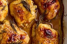 baked chicken thighs with rosemary garnish in a baking dish, ready to be eaten