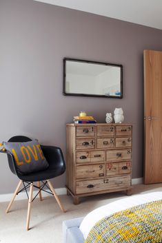 a bedroom with a dresser, mirror and chair