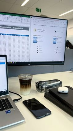 an open laptop computer sitting on top of a desk next to a phone and a cup of coffee