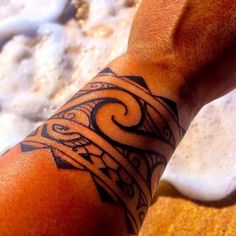 a man's arm with a tattoo on it and sand in the back ground