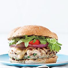 a chicken sandwich with lettuce, tomato and cheese on a blue plate in front of a white background