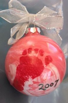 a red ornament with a handprint on it and a bow hanging from the top