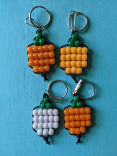 four key chains made to look like candy corn cob charms on a blue background