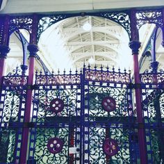 an ornate metal gate with red and blue decorations on it's sides in front of a white building