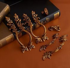 some gold brooches are sitting on a table next to two books and a pair of scissors