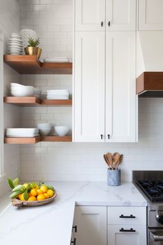 a kitchen with white cabinets and marble counter tops is pictured in this image, there's a bowl of fruit on the counter