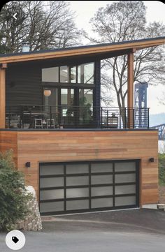 a modern house with wood siding and glass windows on the top floor, along with an attached deck