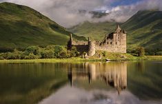 a castle sitting on top of a lake surrounded by mountains