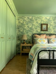 a bedroom with green wallpaper and bed in the corner, next to two closets