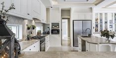 a large kitchen with white cabinets and marble counter tops, along with an island in the middle