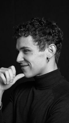 a black and white photo of a young man with curly hair smiling at the camera