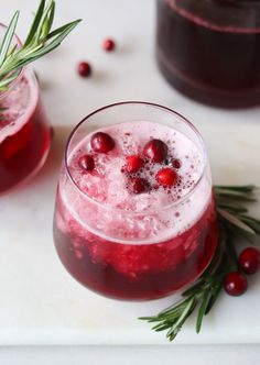 two glasses filled with cranberry punch and garnished with rosemary