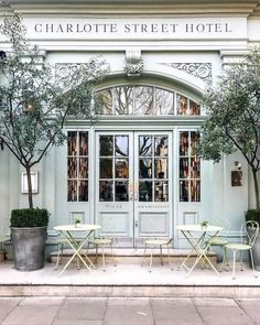 the entrance to charlotte street hotel with tables and chairs in front of it, surrounded by potted trees