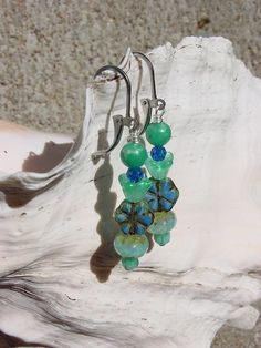 a pair of blue and green glass beaded earrings on a piece of driftwood