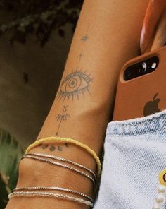 two people with tattoos on their arms and one has an iphone in the other hand