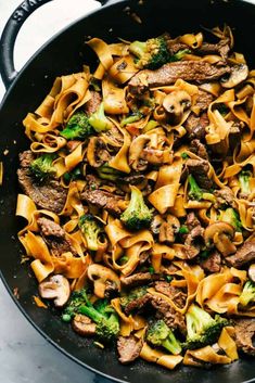 beef and broccoli pasta in a skillet on a marble counter top, ready to be eaten