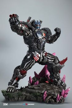 a statue of a robot that is on top of a rock and has his arms in the air