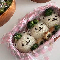 rice balls with broccoli and faces are in a pink plastic bag on the table