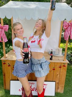 two young women standing next to each other holding up beer bottles