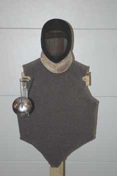 a person wearing a hood and holding a spoon in front of a wall mounted object