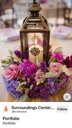 a lantern with flowers on it sitting on top of a table