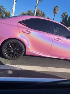 a pink car is parked on the side of the road with palm trees in the background