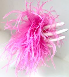 a close up of a pink feather ball on a white tablecloth with two forks