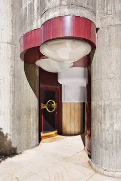 an entrance to a building with red and white columns on either side, and a round light fixture hanging from the ceiling