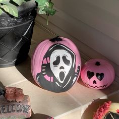 three painted pumpkins sitting on the ground next to a plant and potted plant