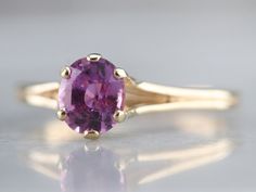 "Truly all about the stone, this elegant, simple, yellow gold mounting frames the stone perfectly while holding it securely. The gemstone pops with color, set with an expertly cut pink Ceylon sapphire. Set low to the finger, this would make a spectacular engagement ring, comfortable to wear with a variety of bands! Metal: 14K Yellow Gold Gem: Ceylon Pink Sapphire 1.02 Carats Gem Measurements: 6.6 x 5.7 mm, Oval Ring Size: 7 Marks: \"14K BDW\" Stamped on the inside band SKU #: UUHQRF82 Each piece Classic Pink Sapphire Ring For Formal Occasions, Formal Gold Sapphire Ring With Pink Sapphire, Formal Pink Sapphire Ring In Yellow Gold, Formal Yellow Gold Pink Sapphire Ring, Yellow Gold Pink Sapphire Birthstone Ring, Classic Pink Sapphire Jewelry In Yellow Gold, Classic Yellow Gold Jewelry With Pink Sapphire, Elegant Pink Sapphire Birthstone Ring With Prong Setting, Classic Yellow Gold Amethyst Birthstone Ring